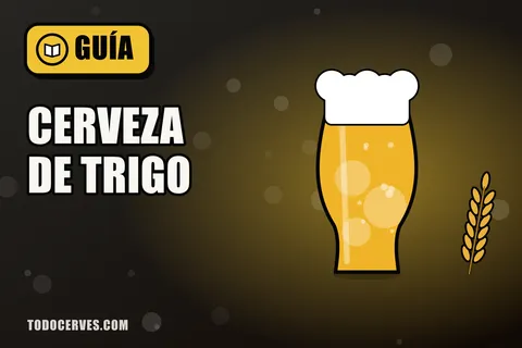 Vaso alto de cerveza de trigo turbia con espuma abundante junto a una espiga de trigo